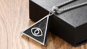 Détail macro du pendentif triangulaire en acier inoxydable avec motif œil sur bois