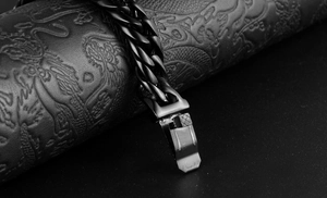 Detailed close-up of a black titanium steel Cuban chain bracelet with a mechanical clasp