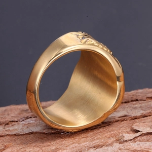 Macro detail of men's gold stainless steel Masonic ring with embossed texture on wood