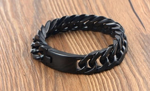 Vue macro d'un bracelet gourmette noir mat avec fermoir lisse sur fond de bois sombre
