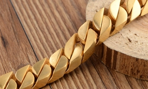 Macro shot of polished gold Cuban link chain bracelet on a natural wood surface