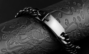 Macro shot of men's black stainless steel Cuban ID bracelet on a textured background