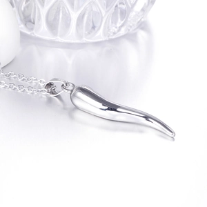 Macro view of mirror-polished silver chili pepper pendant on a fine link chain