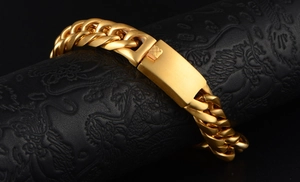 Detail of a bold golden Cuban link bracelet with a polished rectangular clasp on black leather