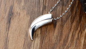 Macro shot of polished silver wolf tooth pendant on a rustic wood background