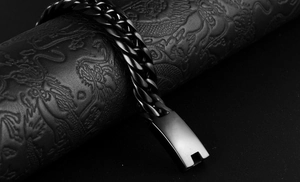 Macro shot of a black stainless steel curb chain bracelet on a dragon embossed pillar
