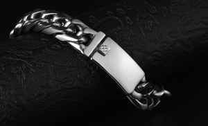 Close-up of silver Cuban chain bracelet with a mirror-finish rectangle buckle on leather