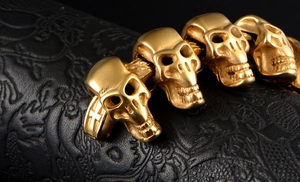 Détail macro du bracelet tête de mort punk doré avec gravures de croix sur maillons