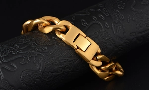 Detail of chunky gold Cuban link bracelet with rectangle folding clasp on black background