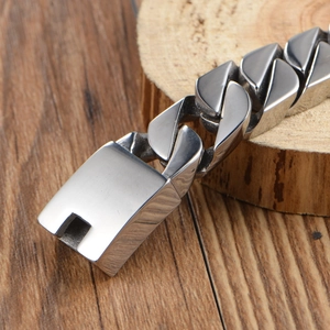 Polished silver stainless steel curb chain bracelet with square box clasp on wood background