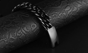 Detail shot of heavy black stainless steel double cuban link bracelet on textured stand