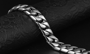 Gros plan d'un bracelet gourmette en acier argenté poli sur un support noir