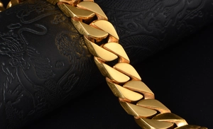 Close-up of thick gold Cuban link bracelet showing polished flat metal links on black pedestal