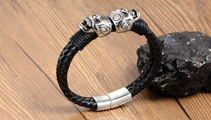 Detailed macro view of woven leather men's bracelet with twin silver skulls and magnetic clasp