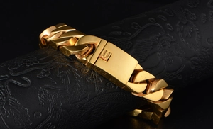 Detailed close-up of wide golden Cuban link bracelet with square clasp on black pedestal