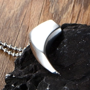 Polished silver stainless steel wolf tooth pendant with ball chain on dark stone