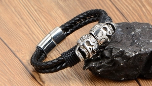 Macro detail of men's punk double skull woven leather bracelet with metal magnetic clasp