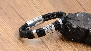 Détail d'un bracelet en cuir tressé pour homme avec fermoir magnétique sur table en bois