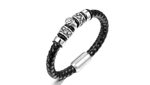 Detailed macro view of black braided leather men's bracelet with silver skull charms