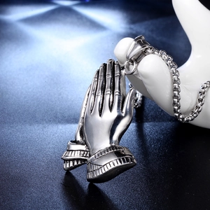 Detail of a polished stainless steel praying hands pendant with an antique finish