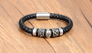 Detailed macro of vintage black braided leather bracelet with silver skull charm and magnetic clasp