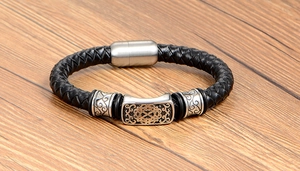 Close-up of woven black leather bracelet with vintage engraved metal beads and magnetic clasp
