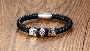 Detail of men's black braided leather bracelet with silver skull and magnetic clasp