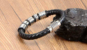 Close-up of woven black leather bracelet with stainless steel Greek key pattern rings