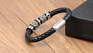 Detailed macro of men's black braided leather bracelet with vintage silver skull beads