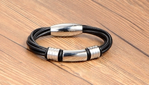 Detail of multi-layer black braided leather bracelet with silver polished magnetic clasp