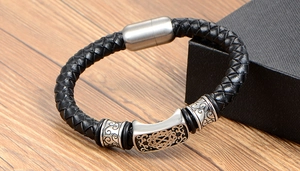 Detail of men's braided black leather bracelet with engraved silver-tone metal magnetic clasp