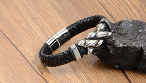 Detail of woven black leather men's punk bracelet with flame-style metal buckle on wood