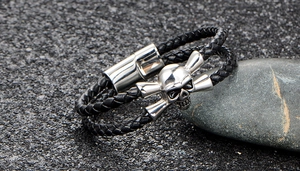 Detail of black woven leather skull bracelet with a cylindrical magnetic clasp on stones