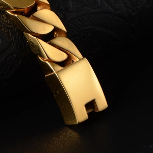 Golden titanium steel Cuban link bracelet for men and women on black leather background