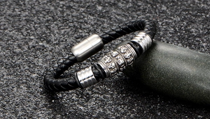 Vue rapprochée du bracelet en cuir tressé noir avec tête de mort et fermoir magnétique