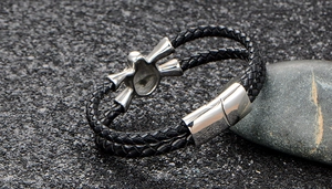 Detail of men's double-wrap black woven leather bracelet with silver skull magnetic clasp