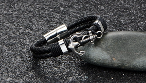 Close-up of black braided leather bracelet with silver anchor charm and magnetic clasp
