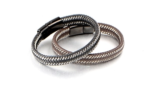 Detail of black and brown braided leather bracelets with metallic magnetic clasps