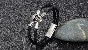 Close-up of double-layer black leather bracelet with silver skull charm and magnetic clasp