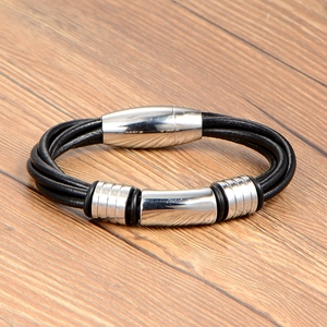 Braided black leather bracelet for men with polished steel magnetic clasp on wood background