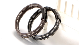 Close-up of woven leather bracelets in black and brown with polished metal clasps