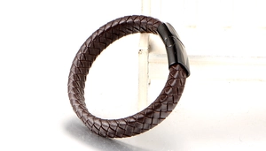 Close-up of men's brown braided leather bracelet featuring a black magnetic metal clasp