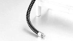 Macro detail of black braided titanium steel cord and polished cylindrical metal clasp