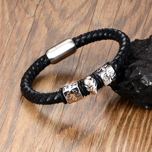 Men's punk leather bracelet featuring skull and cross metal charms on a wooden base
