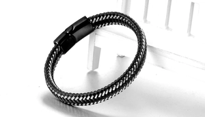 Detail of black and grey braided cord bracelet with matte black magnetic clasp on props