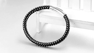 Detail of black and silver woven bracelet with a polished cylindrical magnetic clasp