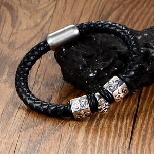 Men's braided black leather bracelet with silver skull and fleur-de-lis metal charms