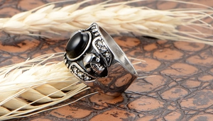 Détail macro d'une bague gothique tête de mort avec pierre noire et métal vintage