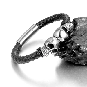 Gros plan d'un bracelet en cuir punk avec deux crânes sur un fond de roche texturée