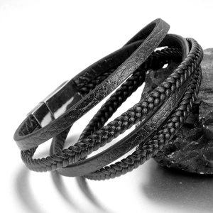 Men's multi-layer black braided leather bracelet with silver magnetic buckle on rock